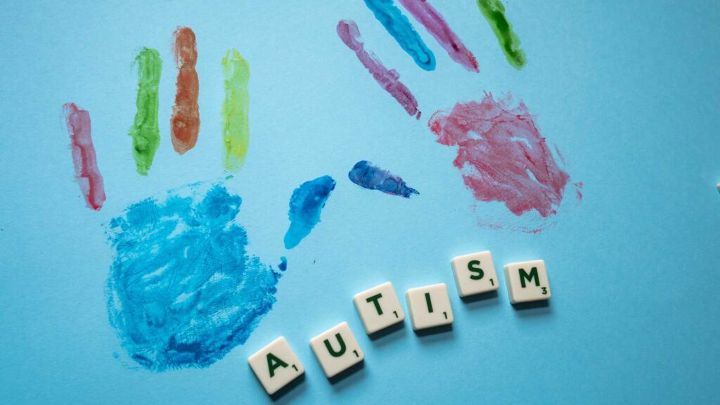 Autism support groups in Georgia: two hand prints left by paint; below is the word “autism” spelled out in Scrabble blocks.